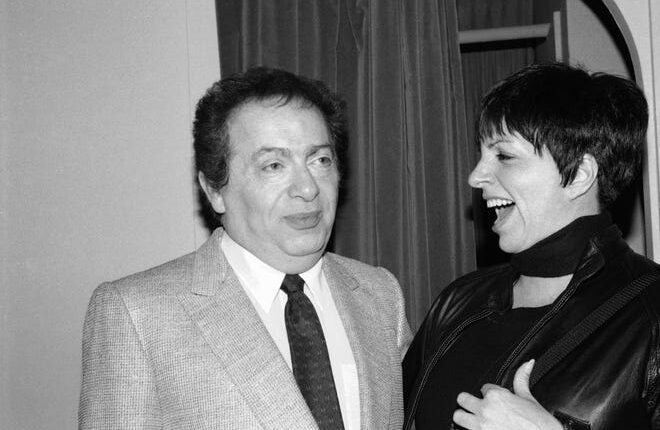 In this February 4, 1991 file photo, Liza Minnelli chats with cartoon character Jackie Mason during a behind-the-scenes visit at the Neil Simon Theater in New York.  Minnelli had stopped by to congratulate Mason on his new Broadway show. 