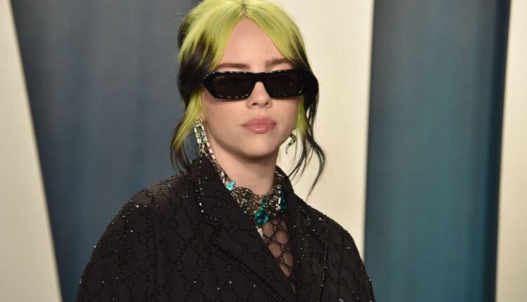 Billie Eilish wearing a black outfit and black sunglasses.