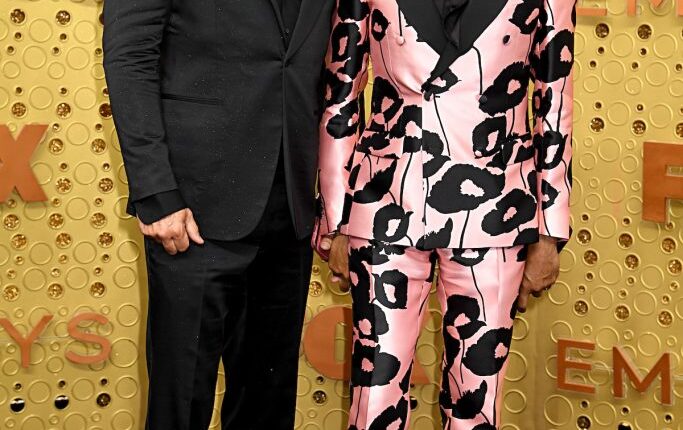 RuPaul and husband Georges LeBar pose together and smile for the camera at an event.